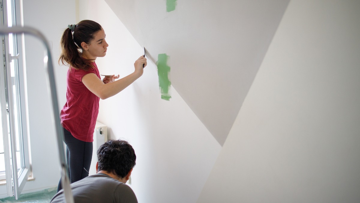 a woman uses a putty knife to patch a wall