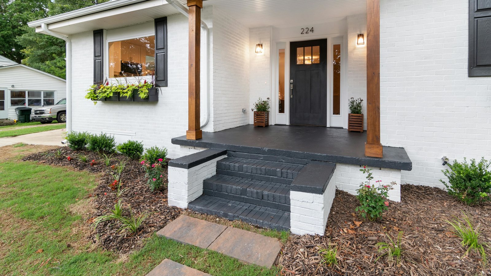 Front view of a charming white brick suburban house with black accents