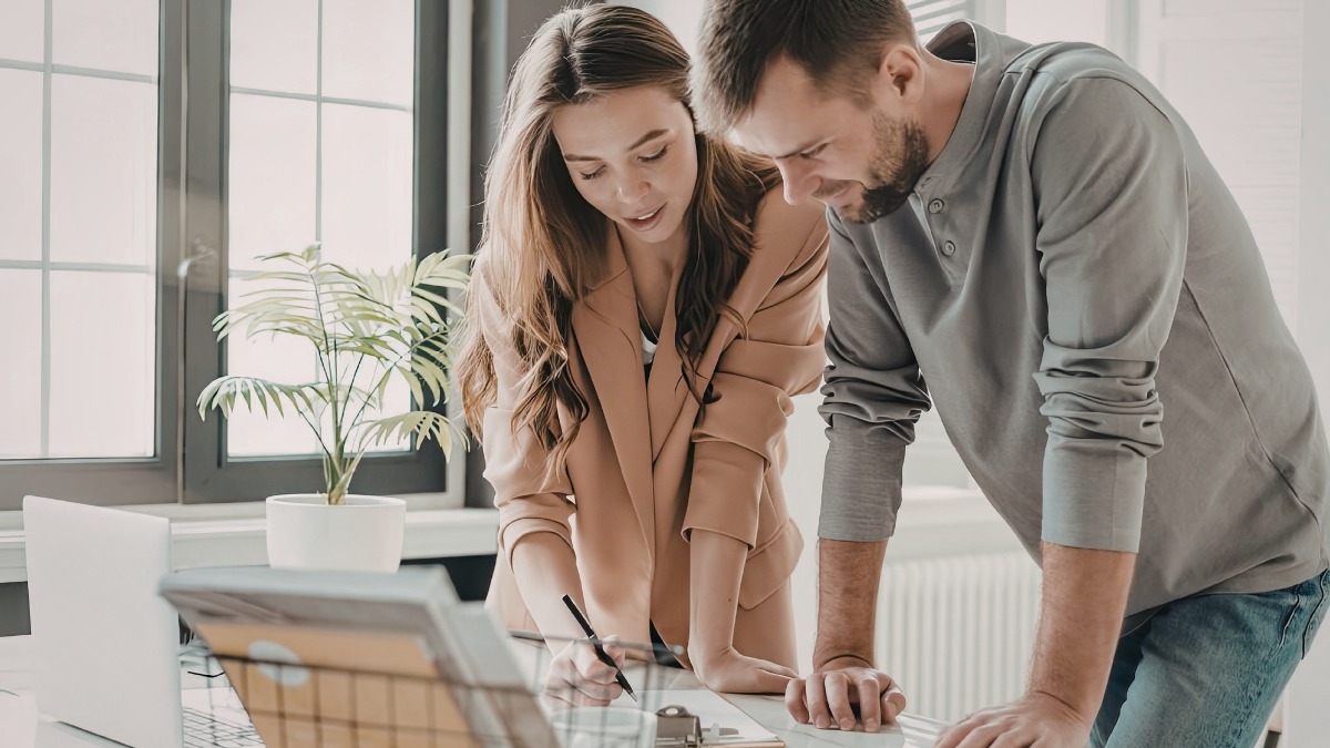 Man and woman leaning over an office desk reviewing documents
