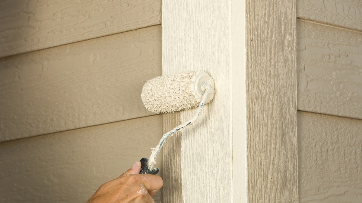 Hand using a roller to apply beige paint