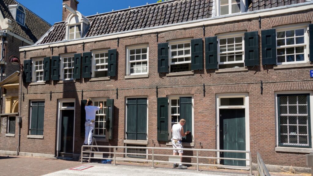 Two painters refurbishing the traditional Dutch brick house facade on a sunny day