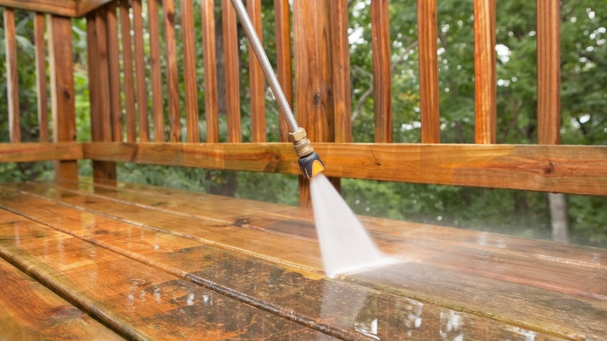 pressure washer cleaning a weathered wood deck