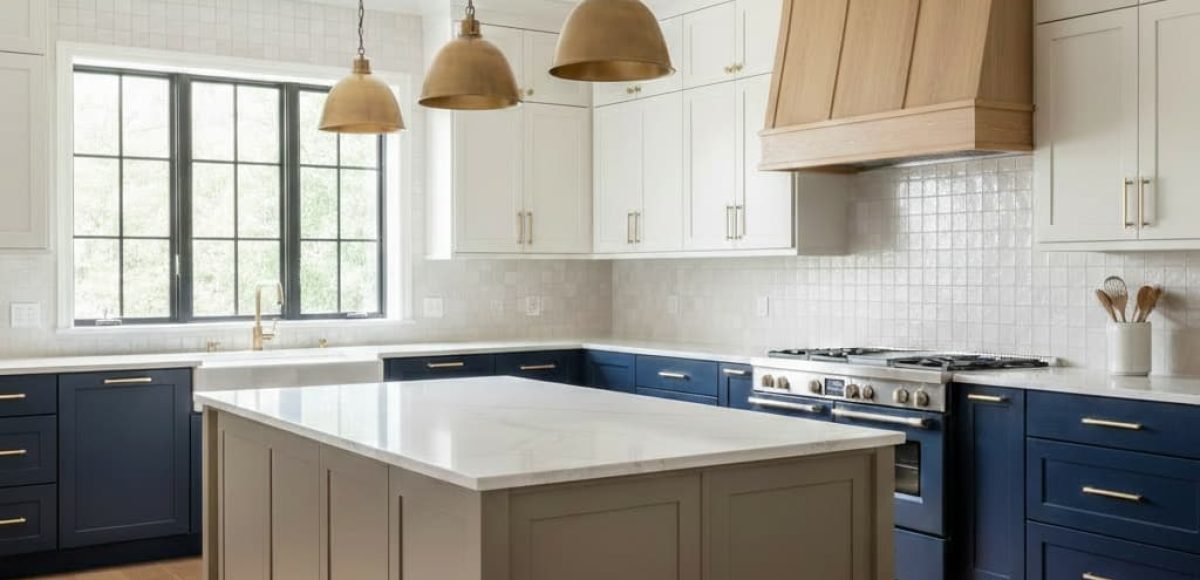 Two-tone kitchen with white upper cabinets, navy lower cabinets, a large island, and wood range hood.